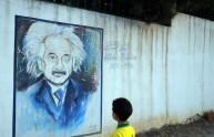 A boy looks at a wall showing a graffiti
