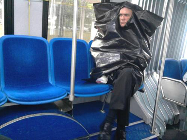 Uomo che indossa la busta di spazzatura nel bus